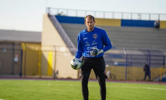 A male soccer goalkeeper holding a ball on field